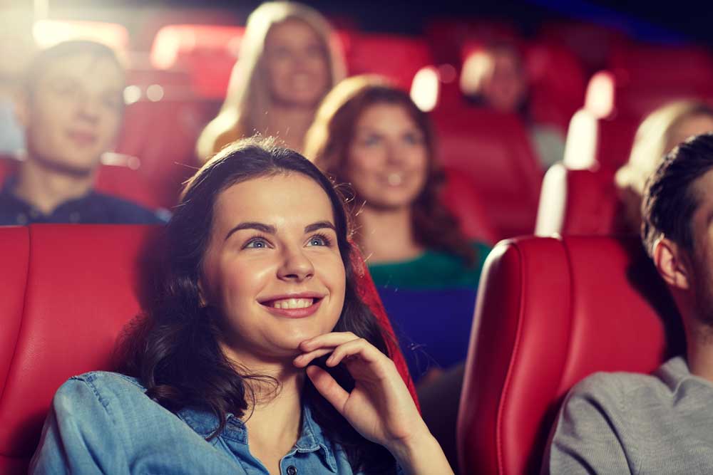 village-of-new-bremen-area-movie-theaters Girl smiles up at movie theater screen with other smiling people behind her